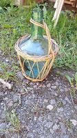 Grüne Glasflasche im Korb  Vintage Deko