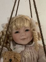 Süsse Porzellanpuppe mit Schaukel