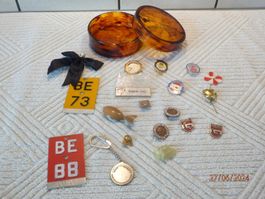 Abzeichen, Stecknadeln, Anhänger, Velonummer in Behälter