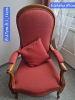 Sessel mit rotem Bezug und Kissen