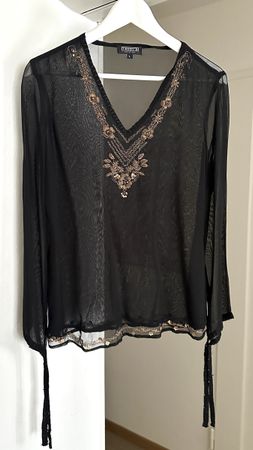 schwarze Bluse mit goldfarbenen Verzierungen am V-Ausschnitt