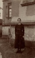 Frau in schwarzem Kleid vor Wohnhaus