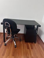 Black office desk with rolling chair and filing cabinet