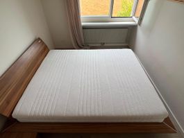 Doppelbett aus Holz, mit Lattenrost und Matratze.