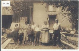 Bauerfamilie mit Kindern vor Bauerhaus