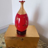 Un joli vase rouge or en porcelaine dans une boîte dorée