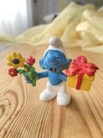 Schlumpf mit Blumen und Geschenk
