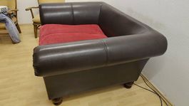 Brauner Sessel / kleines Sofa mit rotem Kissen