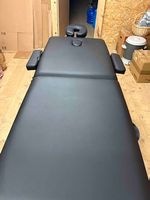 Table de massage en bois réglable, rembourée.