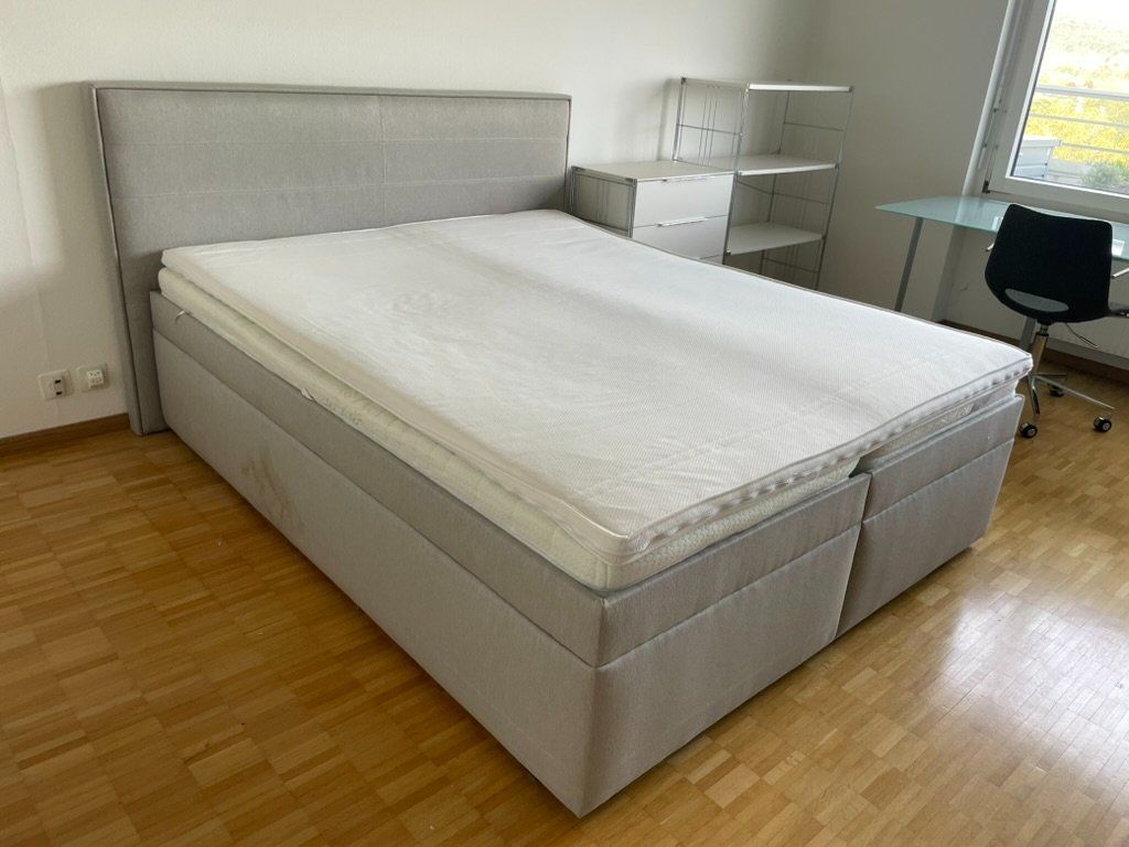 Betten: Hellgraues Doppelbett im Boxspring-Stil mit Kopfteil – Gebraucht aus Zürich von Vichr
