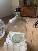 Grosse Glasballon-Flasche im Schutzbehälter