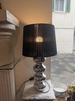 Schicke Lampe mit Chromfuss und schwarzem Lampenschirm.