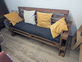Canapé en palettes et divers coussins (gris, jaune et beige)