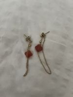 Boucles d'oreilles pendantes dorées avec pierres rouges.