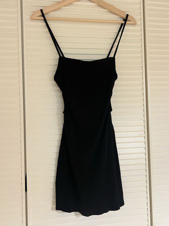 Robe noire courte avec ouverture au niveau des côtes