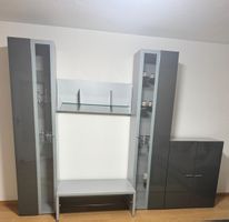 Graue Wohnwand mit Vitrine, Regal und Bank in gutem Zustand