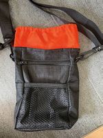 Schwarze Umhängetasche mit orangefarbnerer Beutel