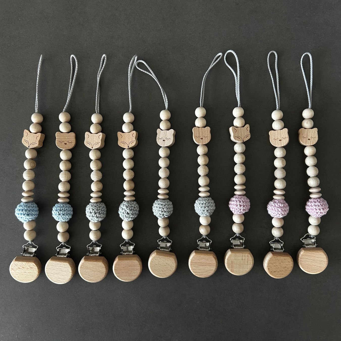 Succhiotti & catenelle porta ciuccio: Nuggikette / Schnullerkette aus Holz in rosa, blau oder grau – Nuovo e nell'imballaggio originale da Münsingen venduto da Yalaa