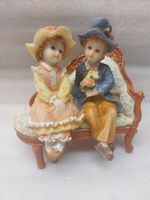 A figurine depicting a romantic couple on a small sofa.