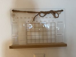 Wandkalender mit Notiztafel und Holzablage mit Stiften