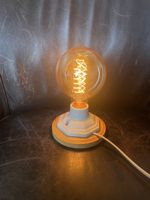 Tischlampe mit Glühbirne und Holzsockel