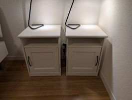 Ein Nachttisch (rechts) weiss mit Fach und Tür.