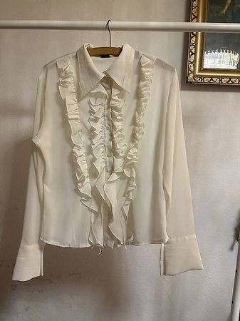 Cream ruffle blouse with long sleeves and button-up front. 