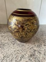 Schöne rote Vase mit goldenen Motiven