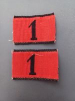 2 Achselnummern 1875/98, schwarze 1 auf rotem Grund