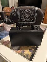Elefante decorativo in legno scuro con intagli bianchi.
