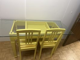 Tisch mit Glasplatte und zwei Stühlen gelb