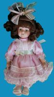 Süsse Porzellanpuppe mit rosa Kleid