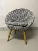 grauer Sessel mit Muster und Holzbeinen