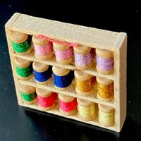 Kleines Regal mit Fadenspulen für die Puppenstube.