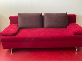 Sofa (Bett-Sofa) rot mit zwei violetten Kissen